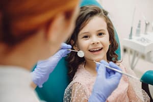 portrait cute little girl laughing looking camera sitting stomatology seat while pediatric stomatologist is ready teeth examination 129180 4524